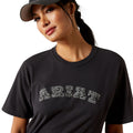 Woman wearing a black t-shirt with text and a cap on a plain background