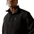 Man wearing a black jacket with a brand logo on a white background
