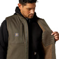 Man wearing a brown vest with a visible brand logo on a white background