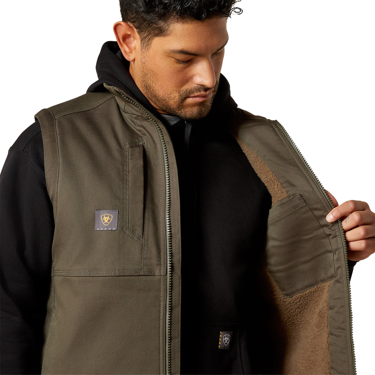 Man wearing a brown vest with a visible brand logo on a white background
