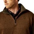 Close-up of a brown pullover with a collar and logo on a white background