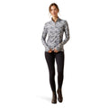 Woman wearing a patterned long-sleeve shirt and black leggings on a white background