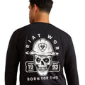 Person wearing a black long-sleeve shirt with a skull and hard hat graphic on the back, featuring 'Ariat Work' branding.