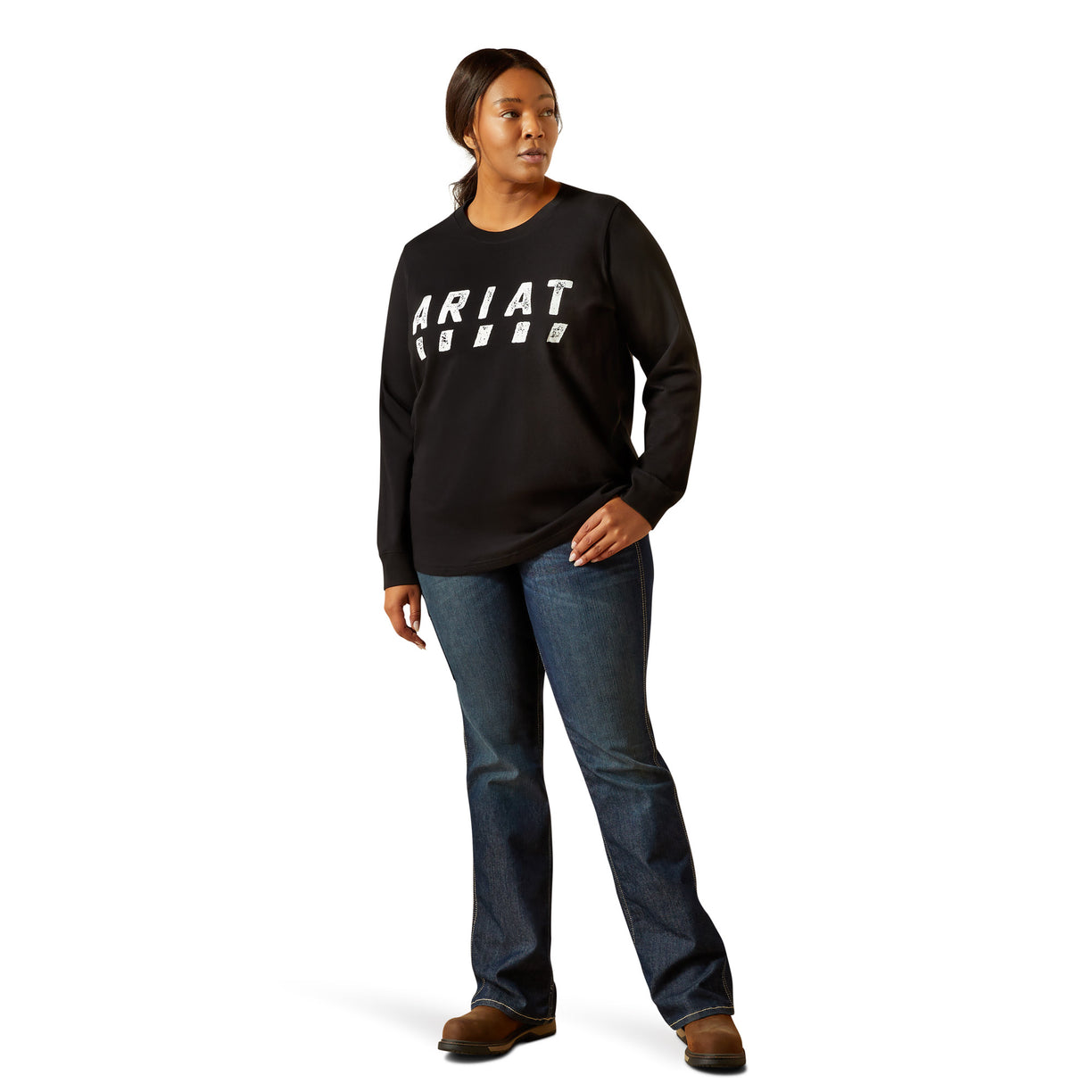 Person wearing a black Ariat sweatshirt and blue jeans on a white background