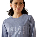 Woman wearing a blue long-sleeve shirt with a brand logo on a white background