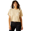 Woman wearing a beige t-shirt with a pocket and dark jeans on a white background