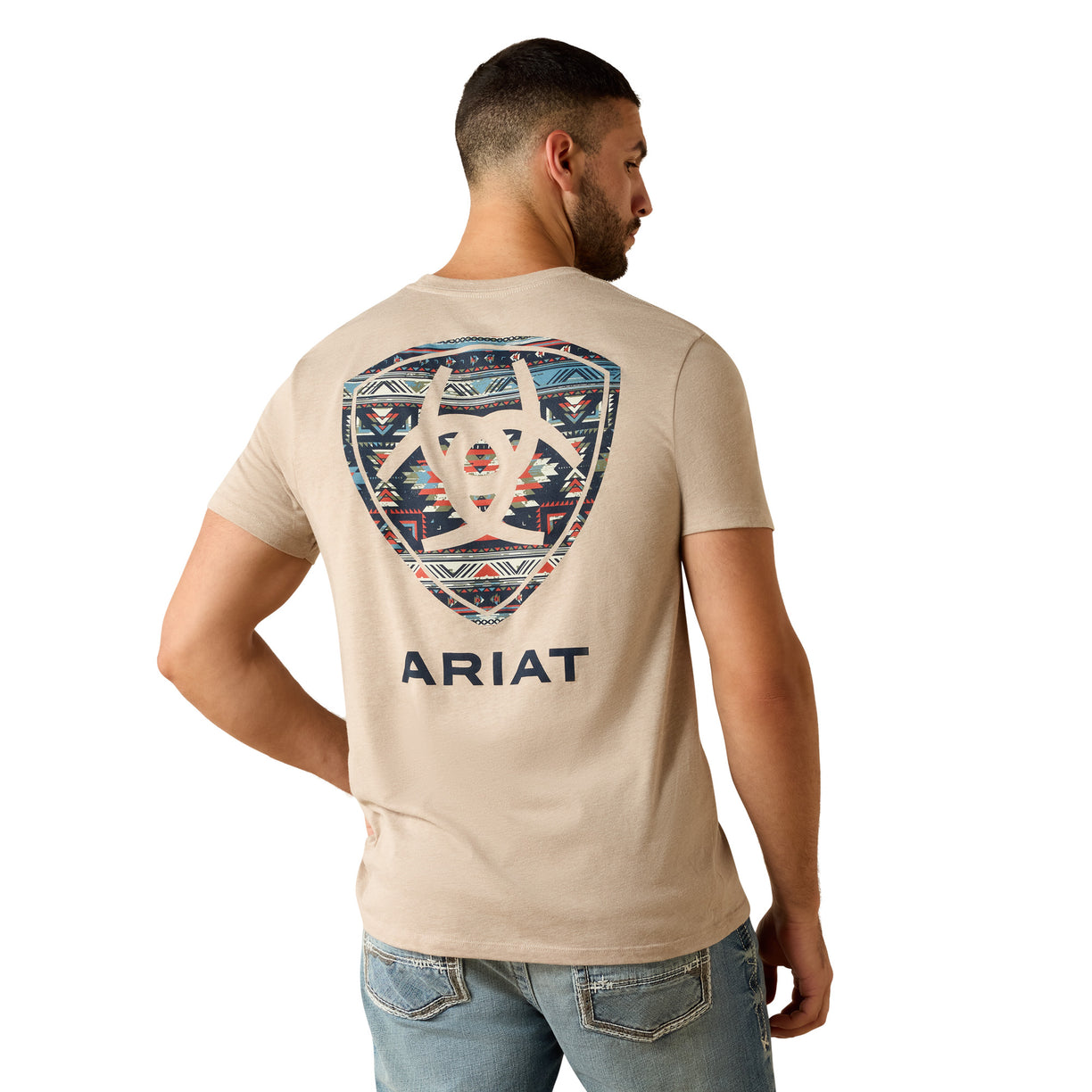 Man wearing a beige t-shirt with a geometric design and 'Ariat' branding on the back.