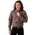 Man wearing a patterned shirt and black pants against a beige background