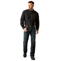 Man wearing a black patterned shirt and blue jeans on a white background