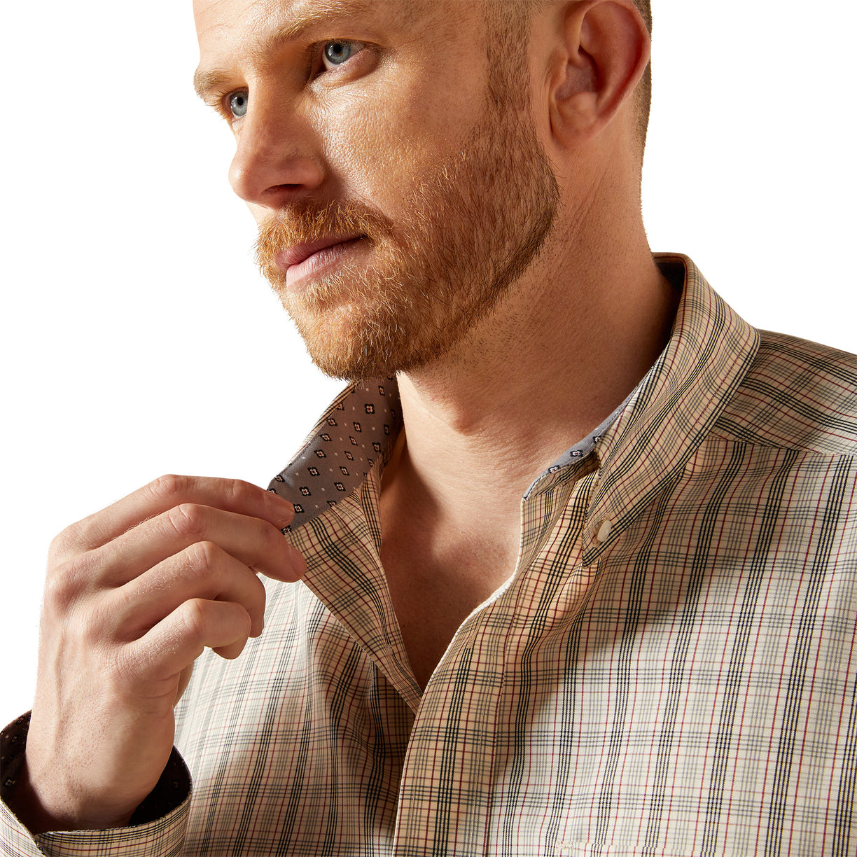 Man adjusting his plaid shirt collar against a white background