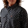 Person wearing a black patterned shirt with a brand logo on a white background