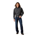 Man wearing a black patterned shirt and blue jeans on a white background