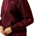 Maroon hoodie with pink accents featuring the Ariat logo on a white background
