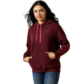 Woman wearing a maroon hoodie with pink drawstrings on a beige background