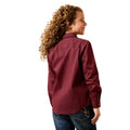 Woman wearing a maroon shirt and blue jeans on a white background