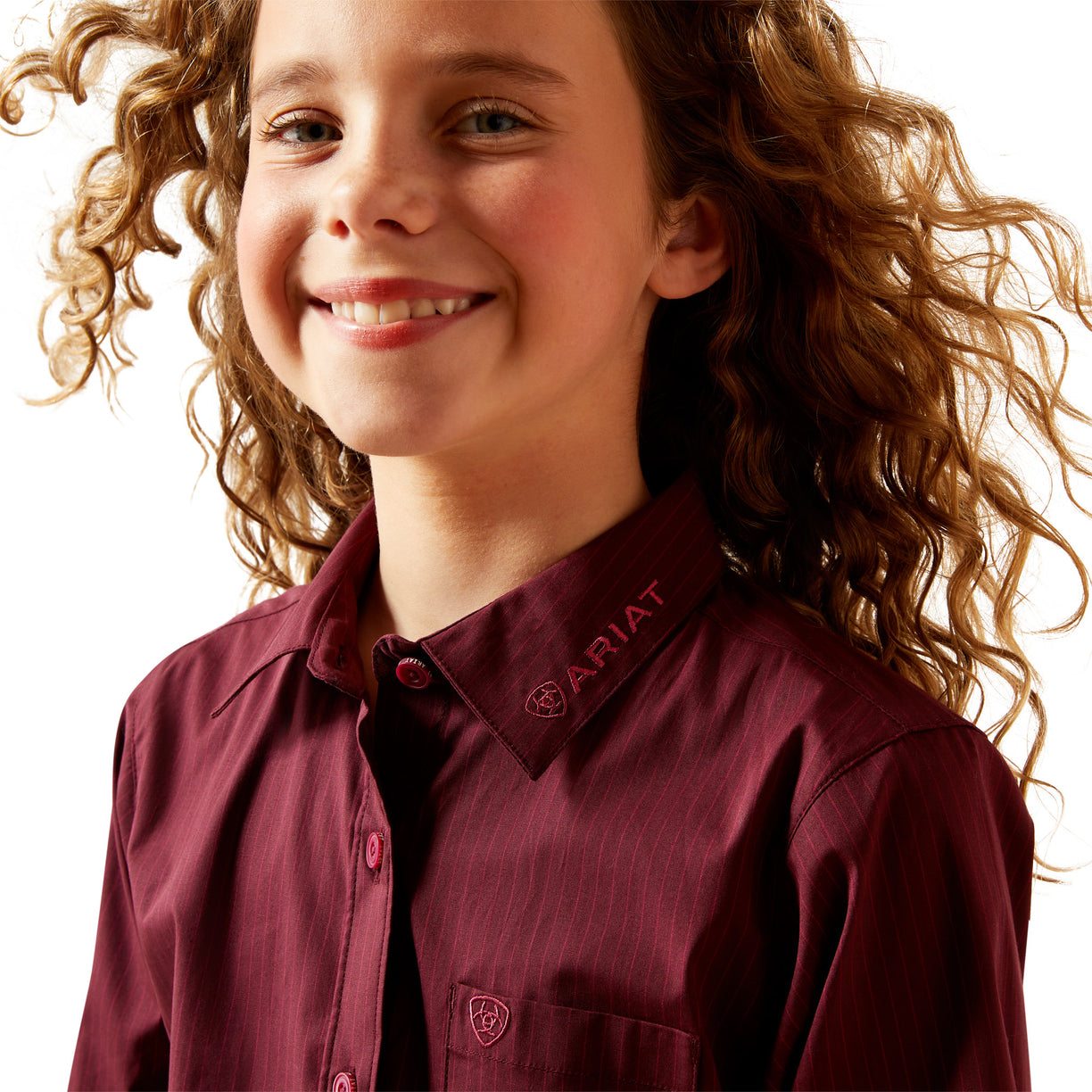 Child wearing a maroon Ariat shirt with a plain background