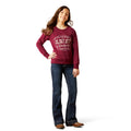Person wearing a maroon sweatshirt with text and blue jeans on a white background