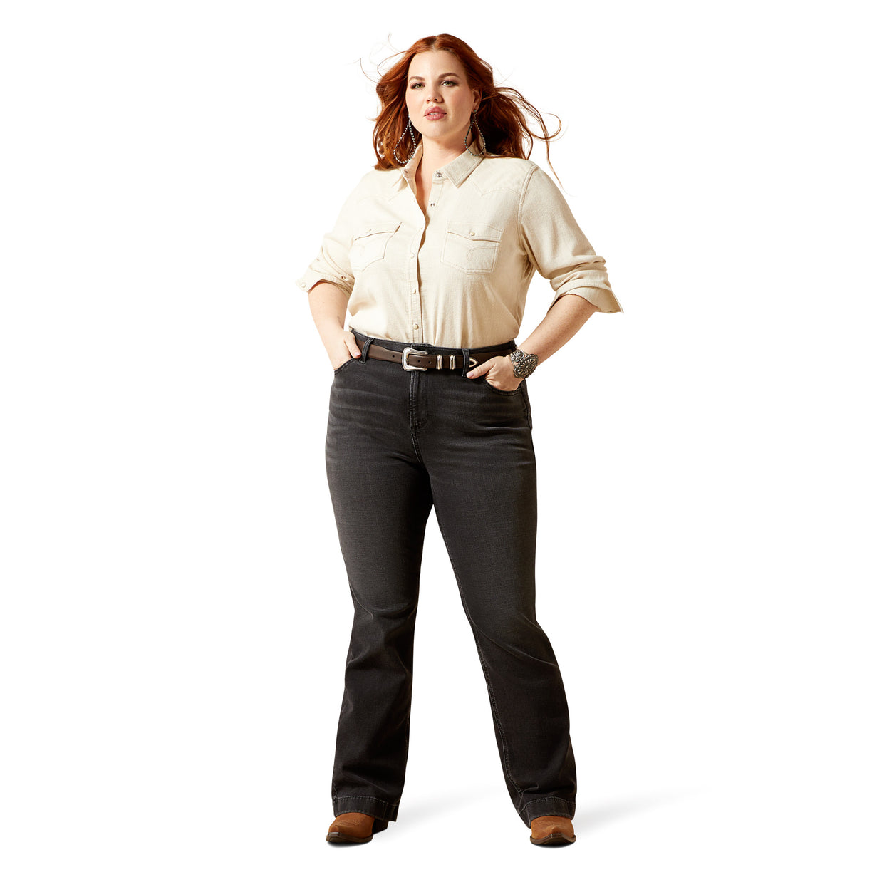 Woman wearing a beige shirt and dark jeans on a white background