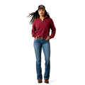 Woman wearing a red pullover, blue jeans, and a cap on a white background