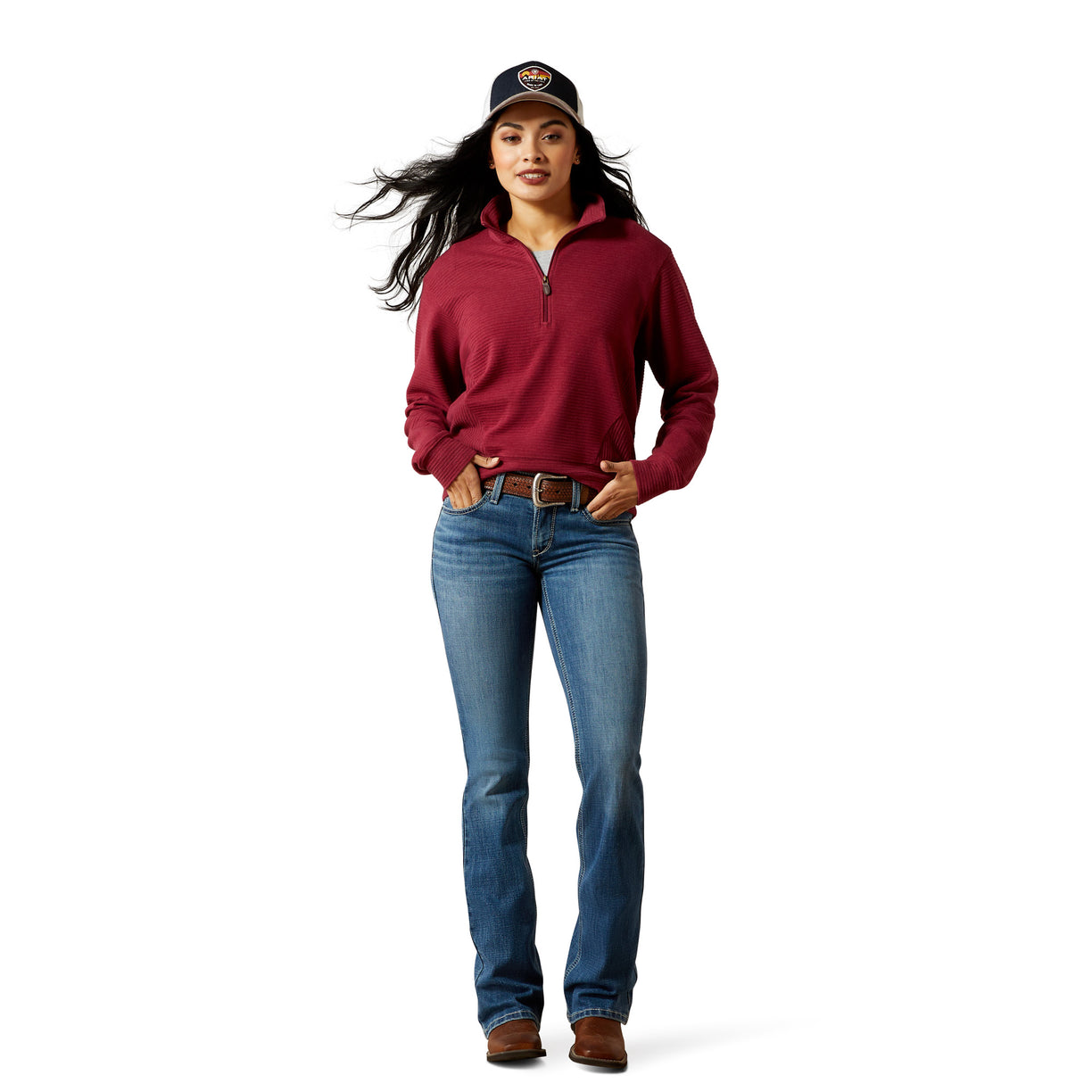 Woman wearing a red pullover, blue jeans, and a cap on a white background