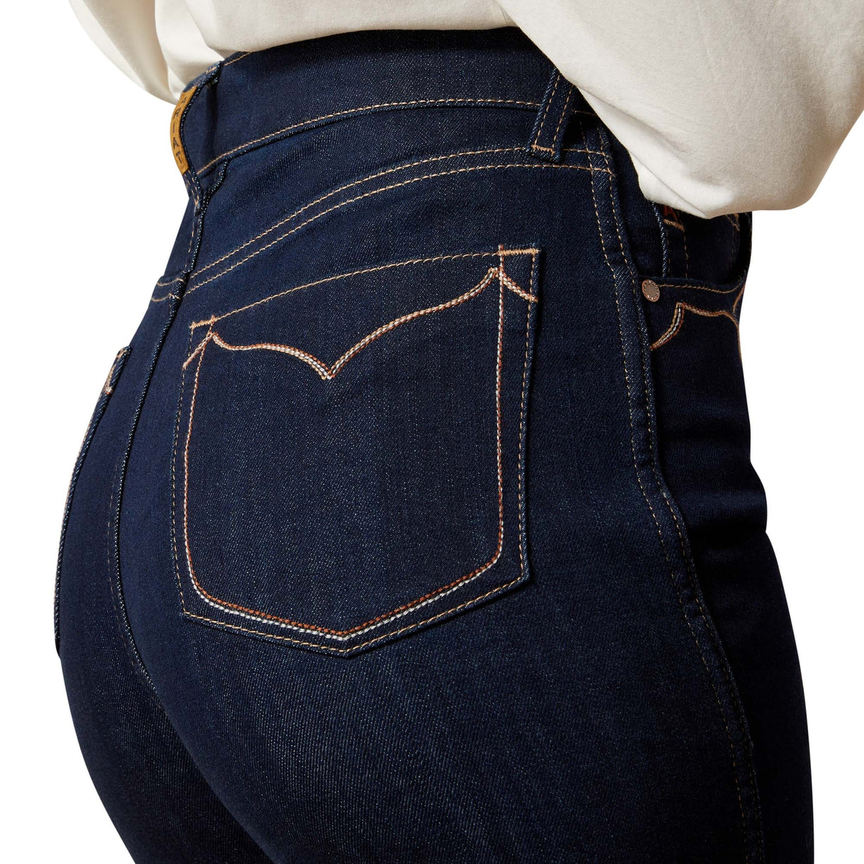 Close-up of dark blue jeans with a white shirt underneath on a white background