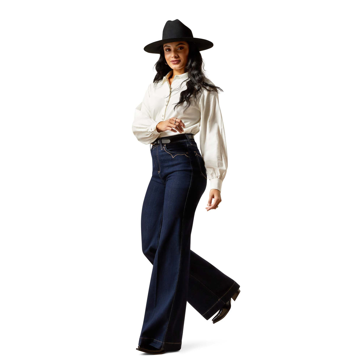 Woman wearing a white blouse and dark blue jeans with a black hat on a white background