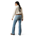 Woman wearing light blue jeans and a beige shirt on a white background