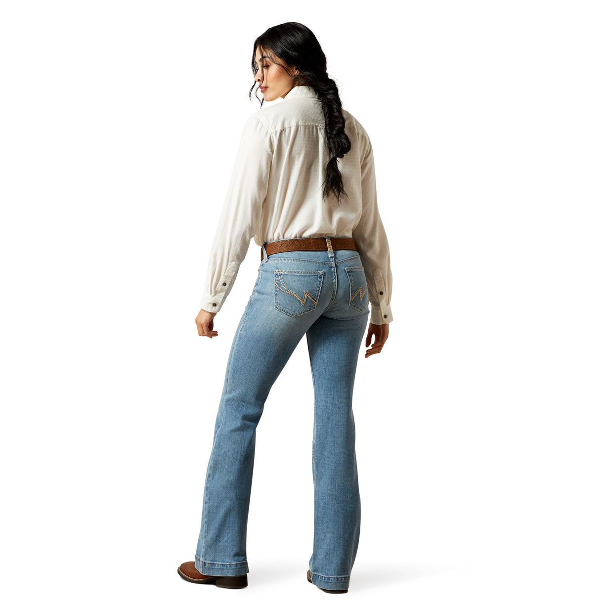 Woman wearing light blue jeans and a beige shirt on a white background