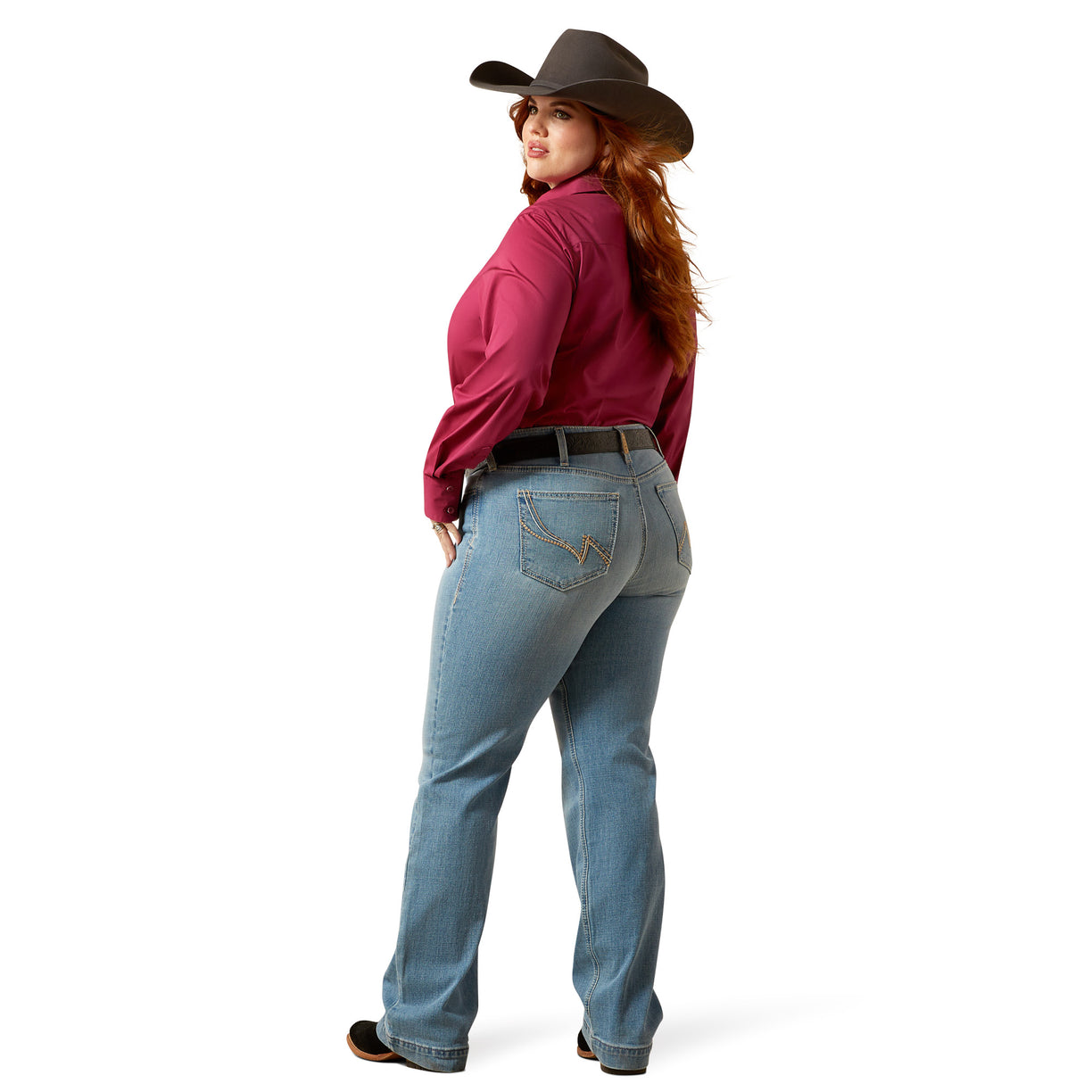 Woman wearing a red shirt, blue jeans, and a cowboy hat on a white background