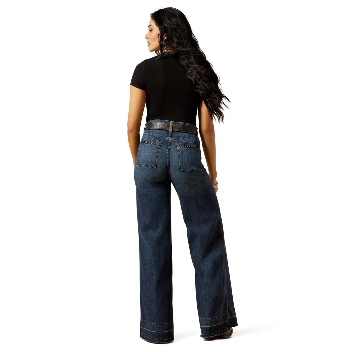 Woman wearing blue jeans and a black top on a white background