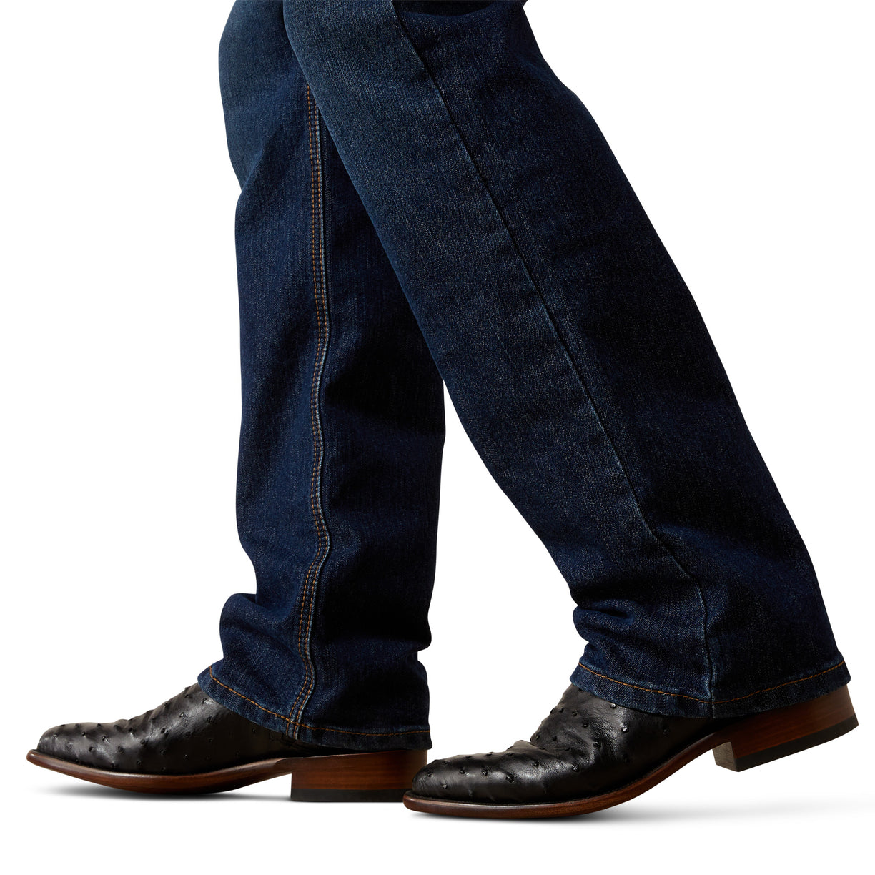 Dark blue jeans worn with brown leather boots on a white background