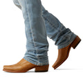 Brown leather shoes worn with light blue jeans on a white background