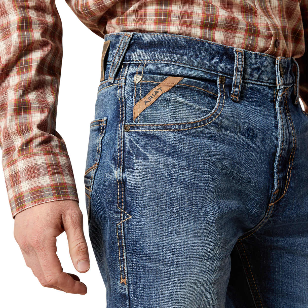 Close-up of blue jeans with a visible brand logo, worn by a person.