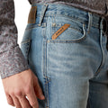 Close-up of blue jeans with Ariat branding on a white background