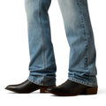 Close-up of blue jeans and black cowboy boots on a white background