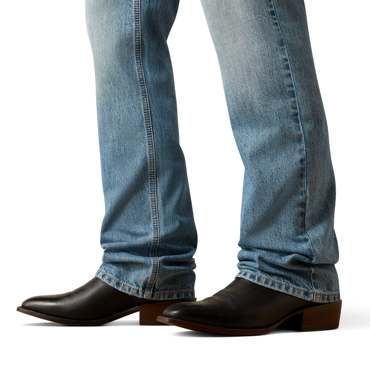 Close-up of blue jeans and black cowboy boots on a white background