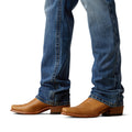 Brown leather boots worn with blue jeans on a white background