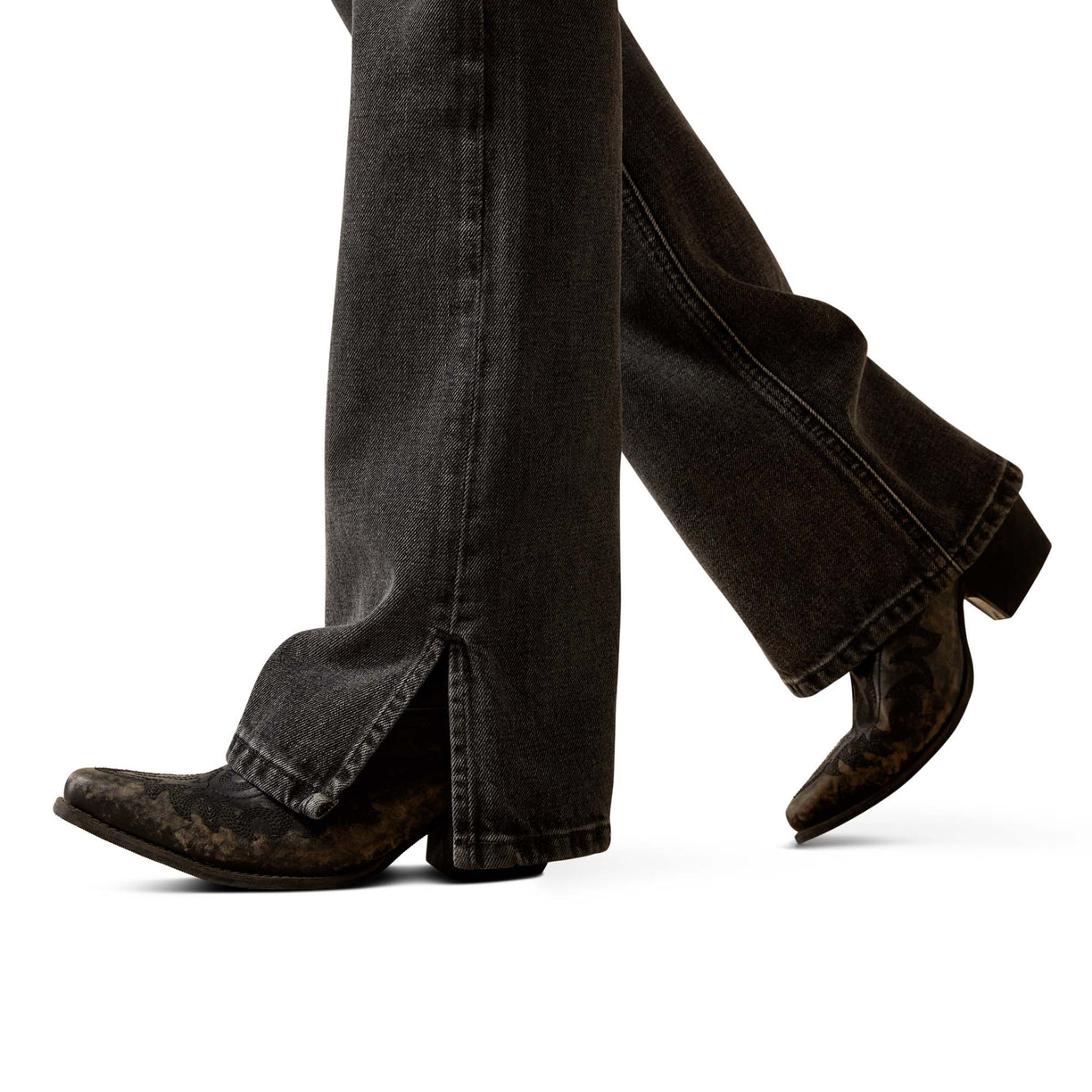 Person wearing black jeans and brown boots on a white background