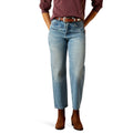 Person wearing light blue jeans and brown shoes on a white background