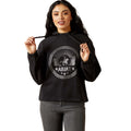 Woman wearing a black hoodie with Ariat logo on a white background