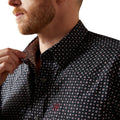 Man wearing a black patterned shirt with a close-up of the collar.