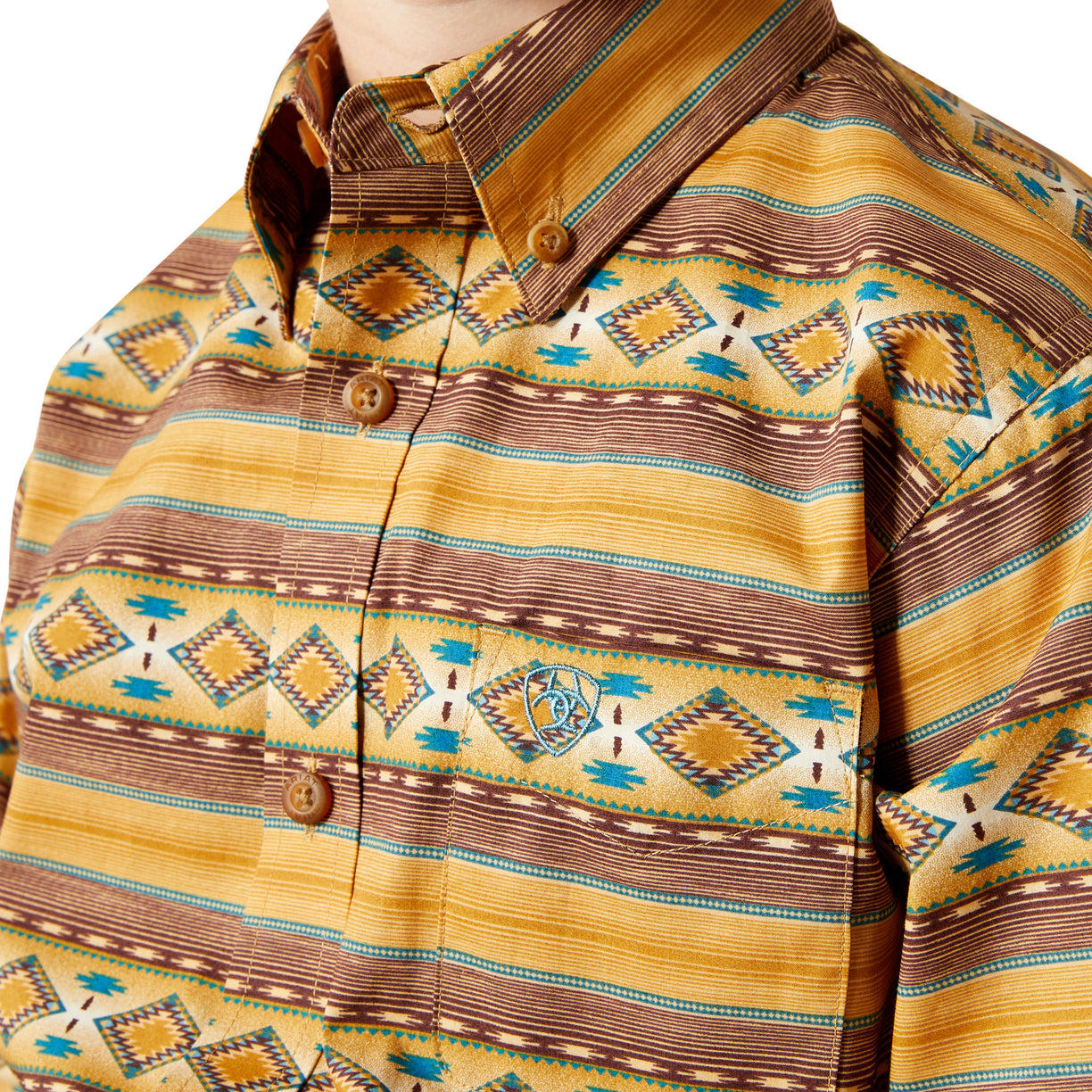 Close-up of a patterned shirt with geometric designs in yellow, brown, and blue.