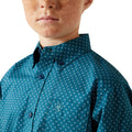 Close-up of a person wearing a teal patterned shirt with a white background