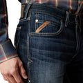 Close-up of blue jeans with Ariat logo on a white background