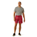 Man wearing a gray t-shirt and red patterned shorts on a white background
