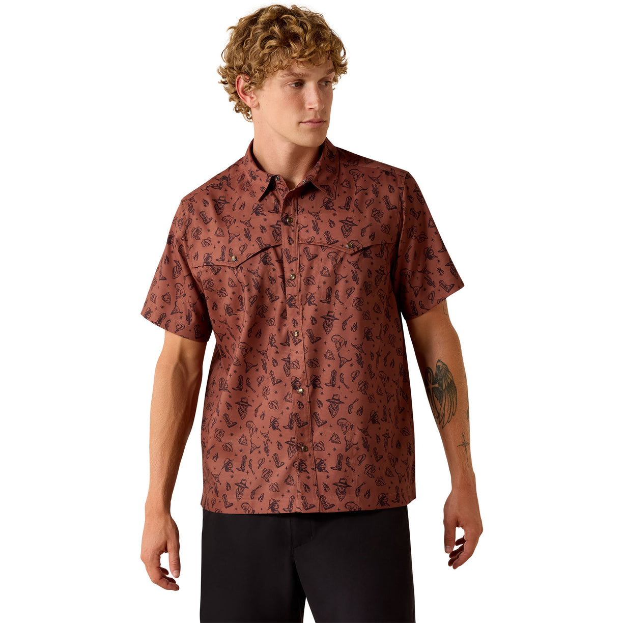 Rust red short-sleeve western snap shirt with an allover cowboy graphic print, worn by a man styled with black pants.
