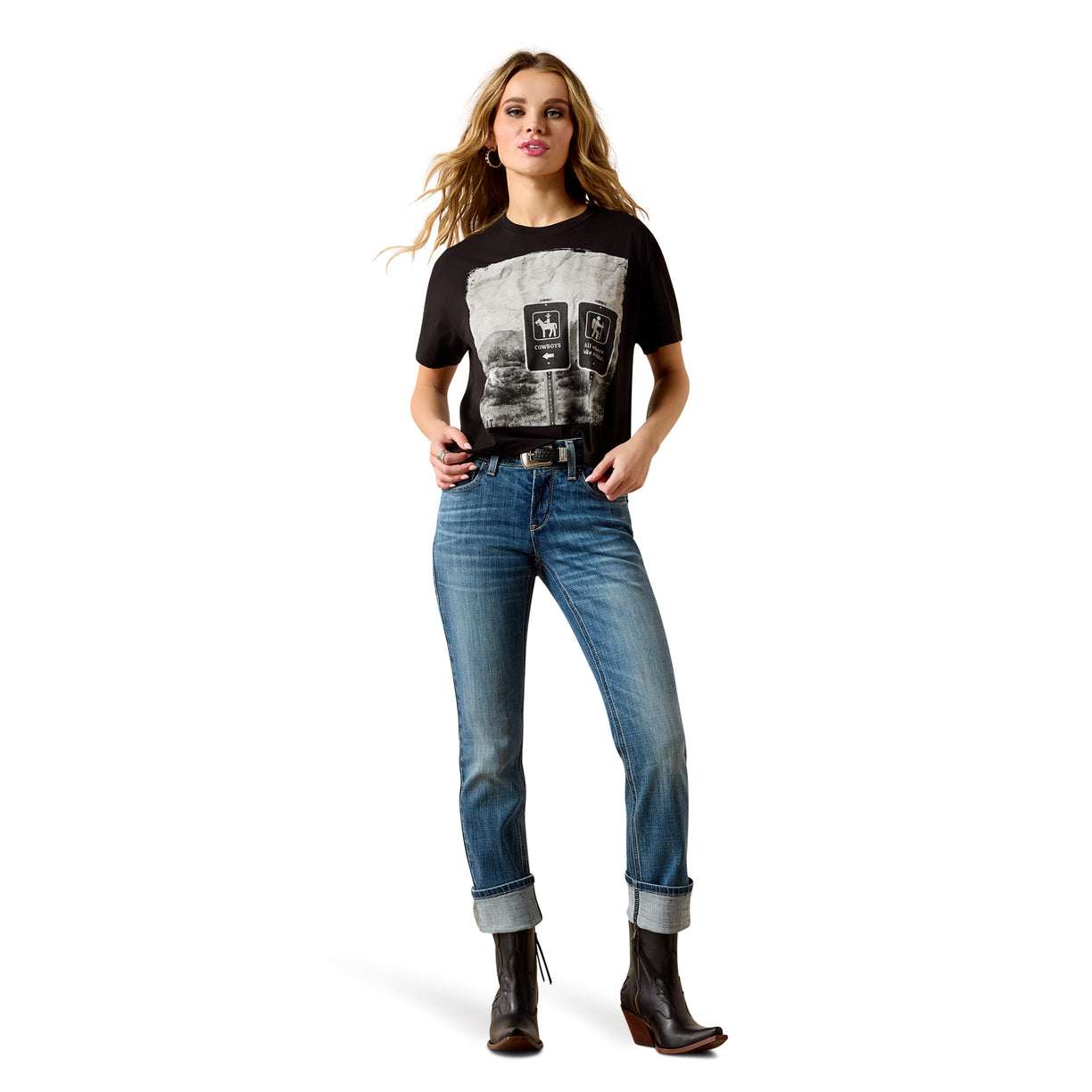 A woman modeling a black short-sleeve graphic T-shirt with a large black-and-white print on the front, paired with blue jeans and dark brown ankle boots, against a plain white background.