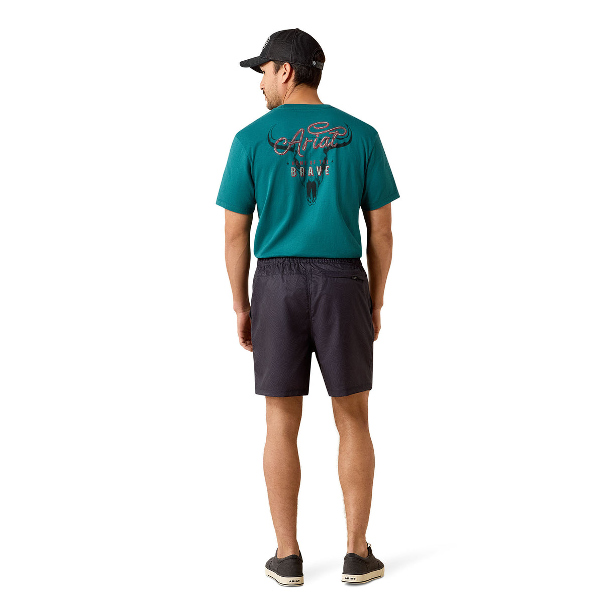 A man shown from the back wearing a teal short-sleeve t-shirt with a graphic on the back, dark charcoal shorts, and a black baseball cap, standing against a plain white background.