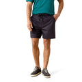 A man wearing dark navy drawstring shorts, a teal t-shirt, and dark gray sneakers, standing against a white studio background.