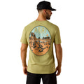 Man wearing a green t-shirt with a desert landscape graphic and 'Ariat' branding.